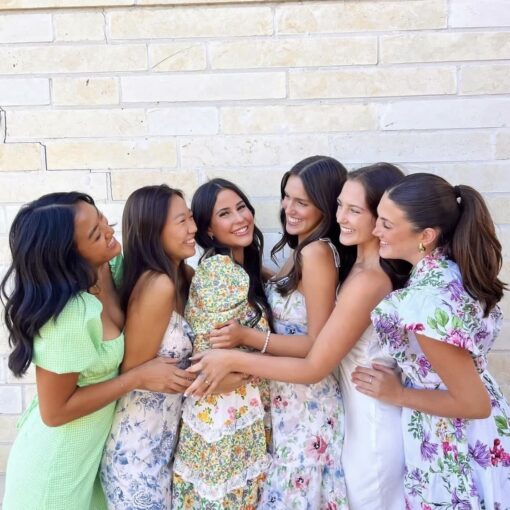 Six CPC members in front of a brick wall, smiling while posing in a line with their arms around each other